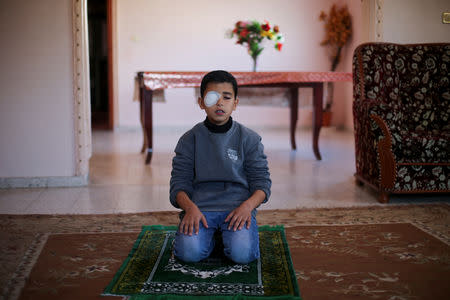 Palestinian boy Mohammad An-Najjar, 12, who was wounded in his eye during a protest at the Israel-Gaza border fence, prays inside his family house, in Khan Younis, in the southern Gaza Strip, January 17, 2019. REUTERS/Ibraheem Abu Mustafa