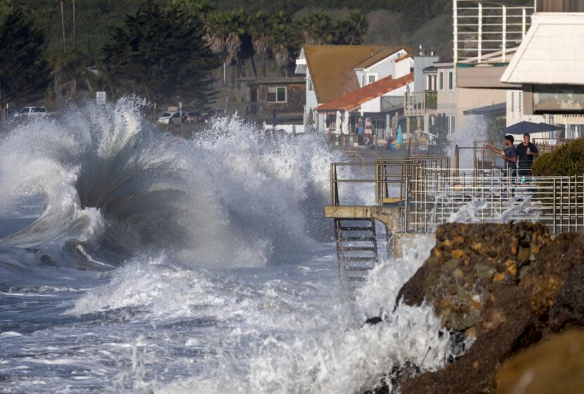 Men watch from a balcony in Faria Beach as huge waves crash on the shore in Ventura.