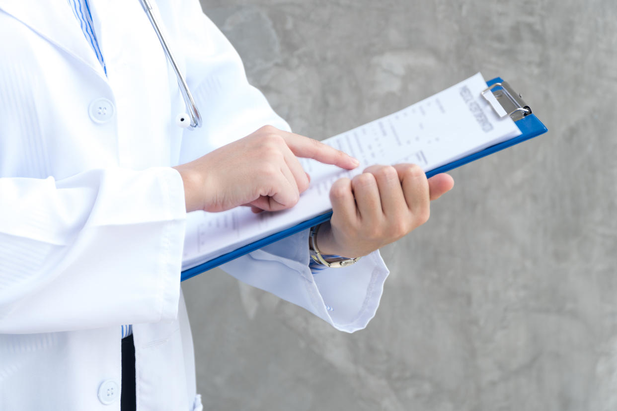 Close-up view of hand woman doctor holding blue clipboard and reading something. Healthcare and medical concept