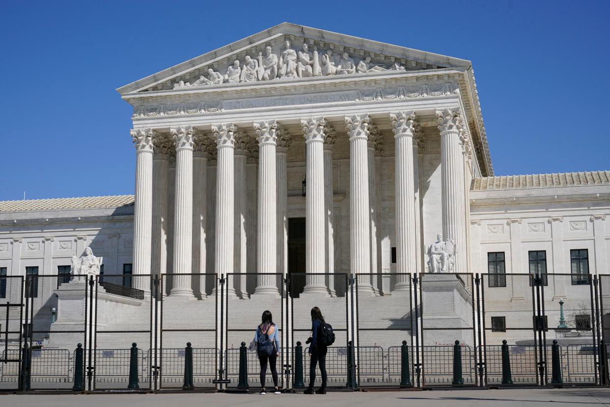 People view the Supreme Court building from behind security fencing on Capitol Hill in Washington, D.C.