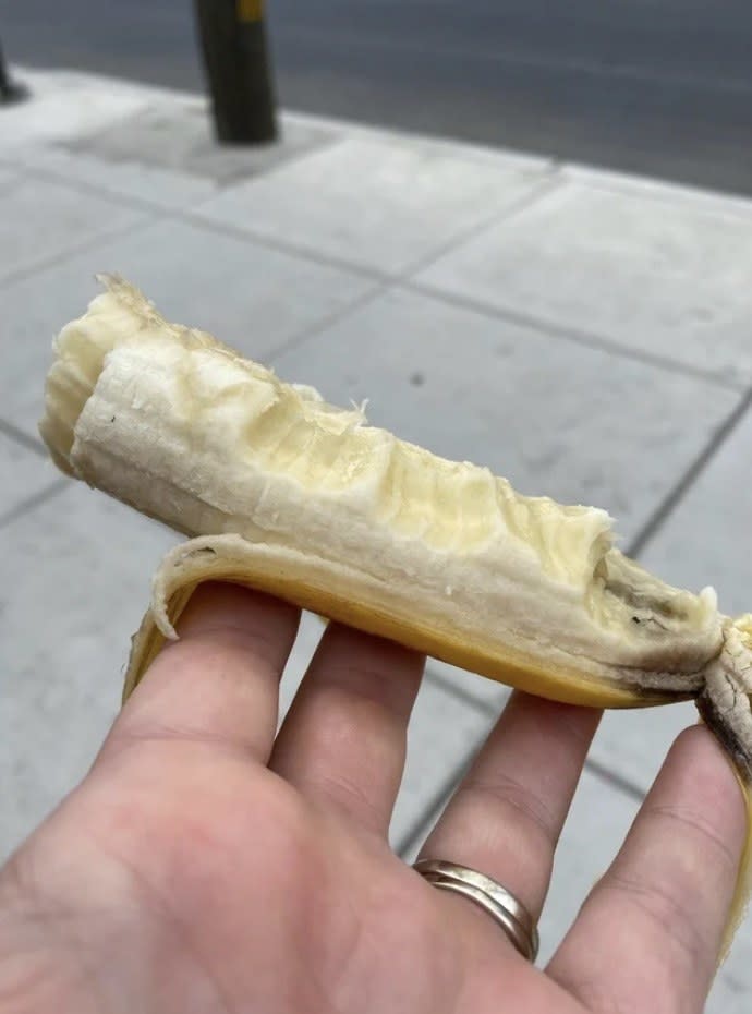 A half-peeled banana with random bites along it lengthwise, held in someone's hand