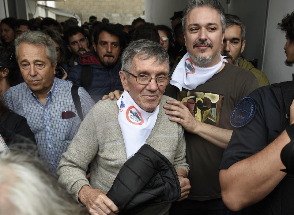 Ex-Ford Motor Co. employees Hector Troiani, center, leaves a courthouse at the end of a sentencing hearing for two former Ford Motor Co. executives charged with crimes against humanity for allegedly targeting Argentine union workers for kidnapping and torture after the country's 1976 military coup, in Buenos Aires, Argentina, Tuesday, Dec. 11, 2018. The court sentenced to prison factory manufacturing director Pedro Muller and security manager Hector Francisco Sibilla, for helping agents of the country's former dictatorship round up Argentine union workers who were tortured and held in military jails. (AP Photo/Gustavo Garello)