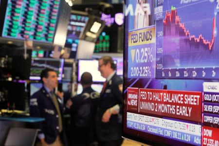 A screen displays the U.S. Federal Reserve interest rates announcement as traders work on the floor of the New York Stock Exchange (NYSE) in New York