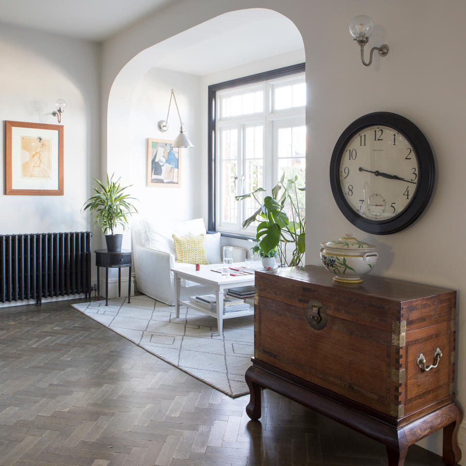 Window seating area under an archway with parquet flooring and cream sofas