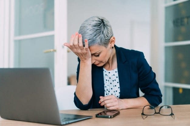 A woman puts her hand to her forehead in frustration during the work day