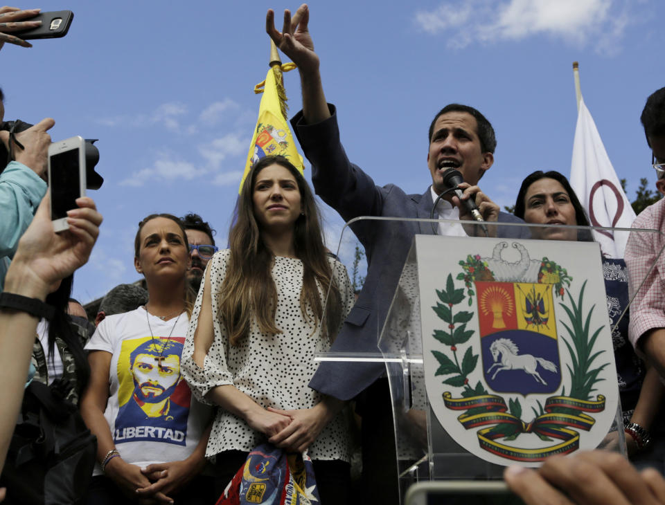 Venezuela's self-declared interim leader Juan Guaido speaks to supporters at a public plaza in Caracas, Venezuela, Saturday, Jan. 26, 2019. Guaido is accompanied by his wife Fabiana Rosales, center left, and Lilian Tintori, left, the wife of jailed opposition leader Leopoldo Lopez. (AP Photo/Fernando Llano)