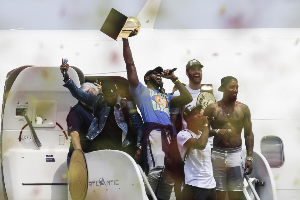 Cleveland Cavaliers' Lebron James, center, holds up the NBA Championship trophy alongside teammates Kyrie Irving, left, Kevin Love, rear right, J.R. Smith, right, and Tristan Thompson, front,   at the airport in Cleveland, Monday, June 20, 2016. (AP Photo/John Minchillo)