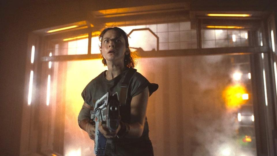 A scared young woman holds a large gun in Alien: Romulus