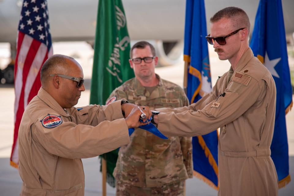 U.S. Air Force Maj. Joseph Rush (right), 908th Expeditionary Air Refueling Squadron (EARS) commander, and Brig. Gen. Akshai Gandhi (left), 378th Air Expeditionary Wing commander, roll up the 908th EARS <u>guidon</u> during an inactivation ceremony at Prince Sultan Air Base, Oct. 4, 2023. <em>U.S. Air Force photo by Tech. Sgt. Alexander Frank</em>