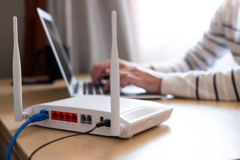 Selective focus at the router.  Internet router connection on the work table with the obscure cable man in the background.  Fast and high speed internet connection from a fiber line with a LAN cable connection.