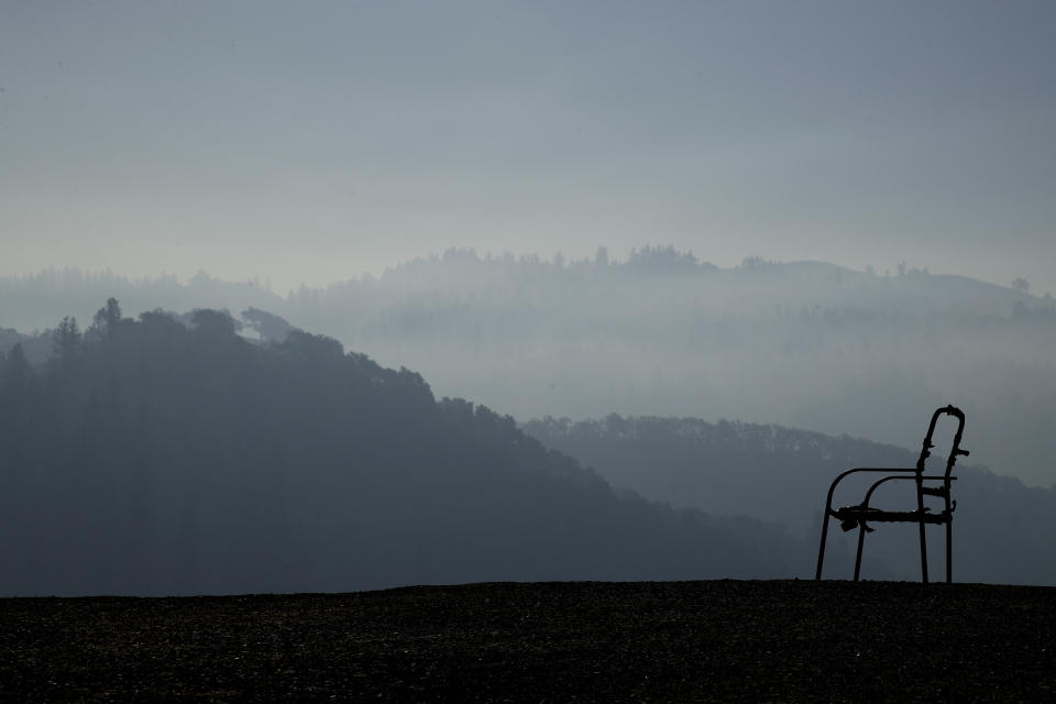 A charred lawn chair overlooks a valley filled with smoke from the Kincade Fire near Healdsburg, Calif., Nov. 1, 2019. (AP Photo/Charlie Riedel)