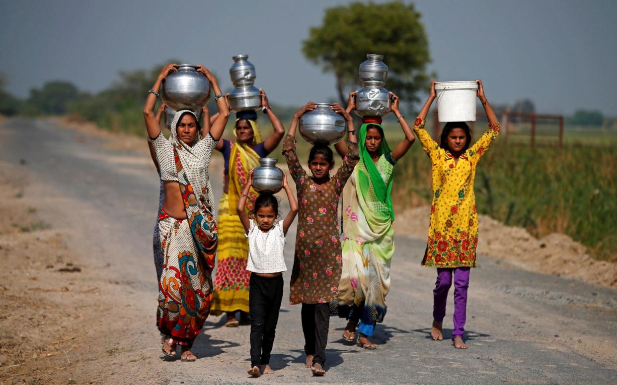 Women and girls carrying water at Fangadi Village on the outskirts of Ahmedabad - REUTERS