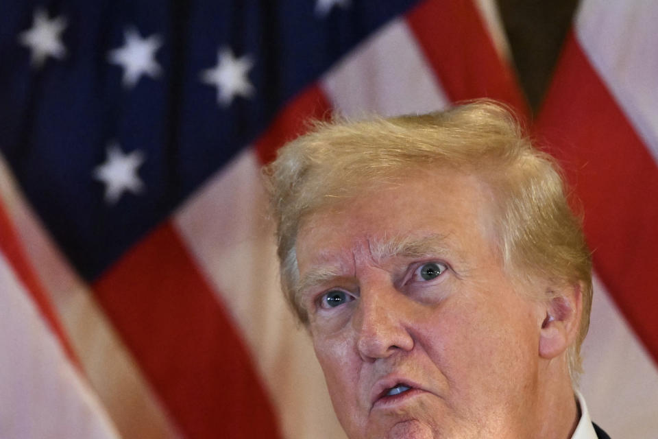 Donald Trump speaks in front of an American flag backdrop