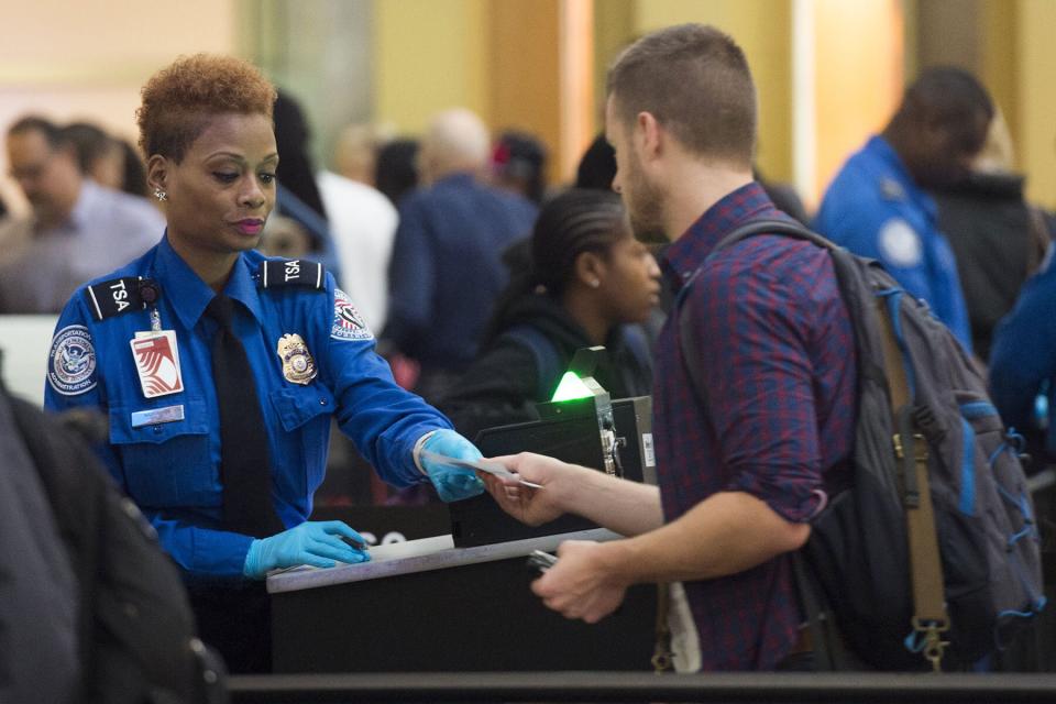 A TSA Agent checks the ID's of passengers as they pass through a security checkpoint on the way to their flights at Reagan National Airport in Arlington, Virginia