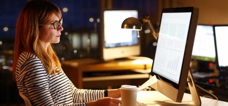 woman sitting in front of computer in office late at night