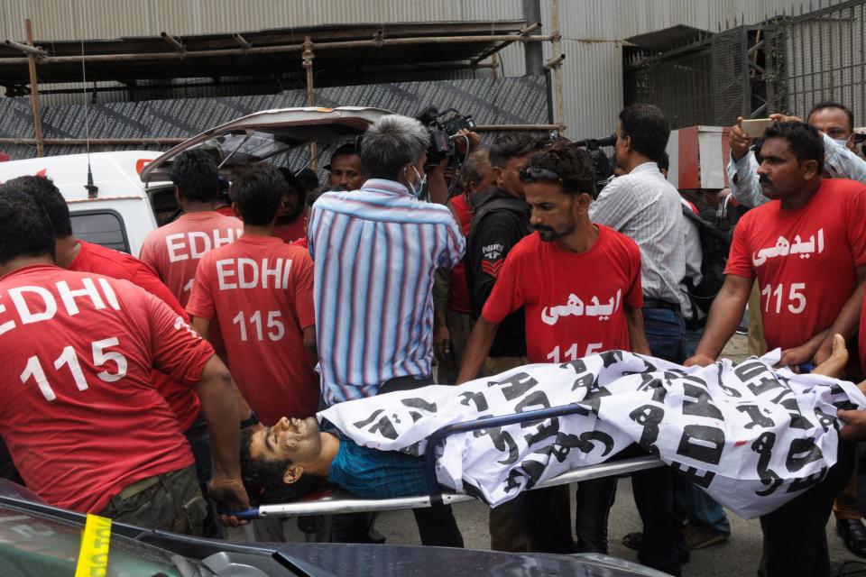 EDITORS NOTE: Graphic content / Edhi volunteers move the body of an alleged gunman from outside the Pakistan Stock Exchange building in Karachi on June 29, 2020. - At least six people were killed after gunmen attacked the Pakistan Stock Exchange in Karachi on June 29, police said, with one policeman among the dead after the assailants opened fire and hurled a grenade at the trading floor. (Photo by - / AFP) (Photo by -/AFP via Getty Images)