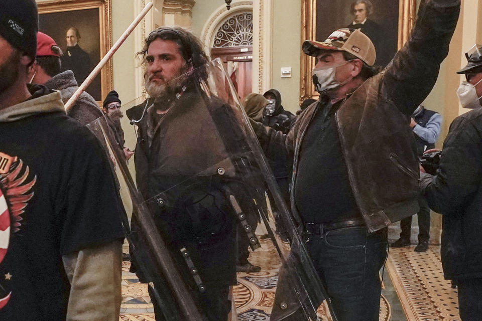 FILE - Rioters, including Dominic Pezzola, center with police shield, are confronted by U.S. Capitol Police officers outside the Senate Chamber inside the Capitol, Wednesday, Jan. 6, 2021, in Washington. A federal jury is scheduled to hear a second day of attorneys’ closing arguments in the landmark trial for former Proud Boys extremist group leaders charged with plotting to violently stop the transfer of presidential power after the 2020 election.(AP Photo/Manuel Balce Ceneta, File)