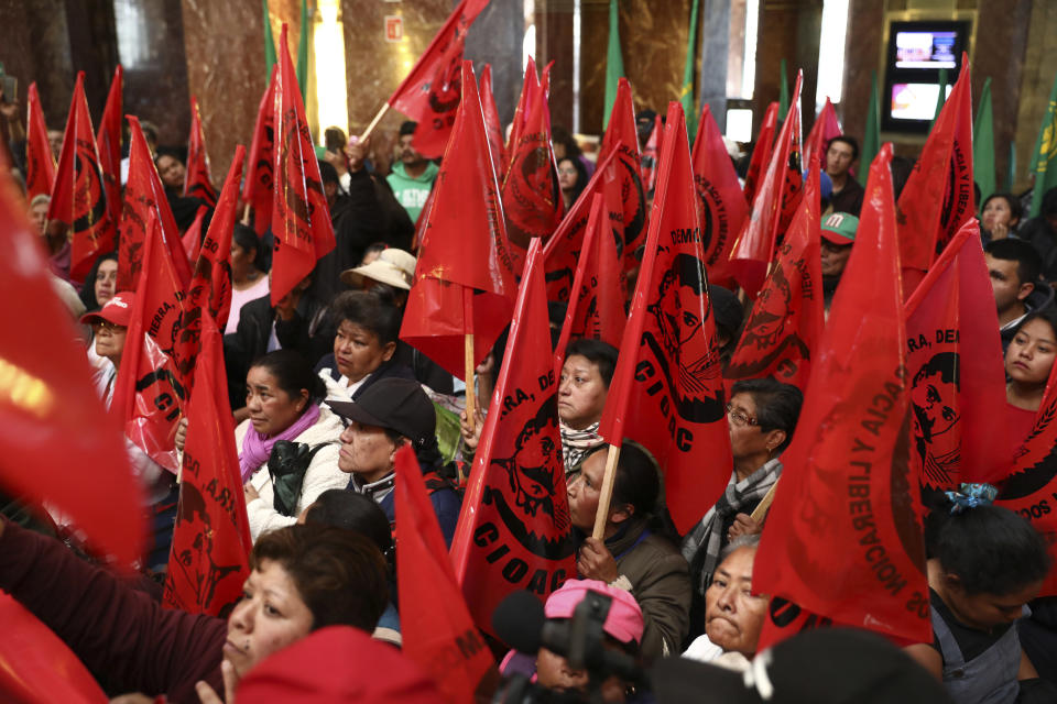 Farm workers block the entrance of the Fine Arts Palace to protest against a painting showing 1910-17 Mexican revolutionary hero Emiliano Zapata nude, wearing high heels and a pink, broad-brimmed hat, straddling a horse, in Mexico City, Tuesday, Dec. 10, 2019. The work by Fabian Chairez is part of an exhibit about Zapata in one of Mexico City's premiere arts venues, the Fine Arts Palace. (AP Photo/Eduardo Verdugo)