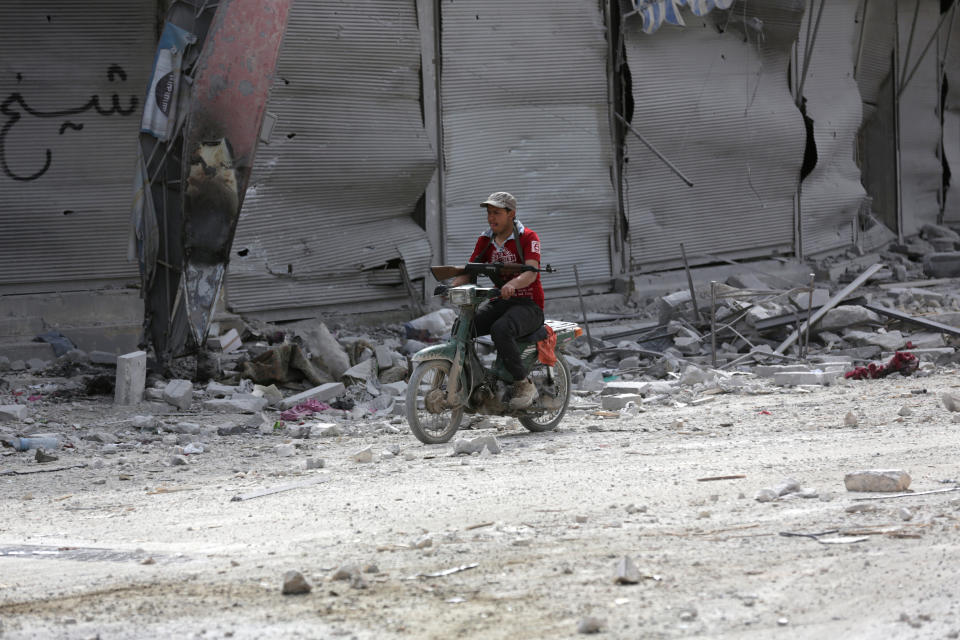 A man rides a motorcycle while carrying his weapon near damaged buildings in the northern Syrian town of al-Bab, Syria, February 28, 2017. REUTERS/Khalil Ashawi