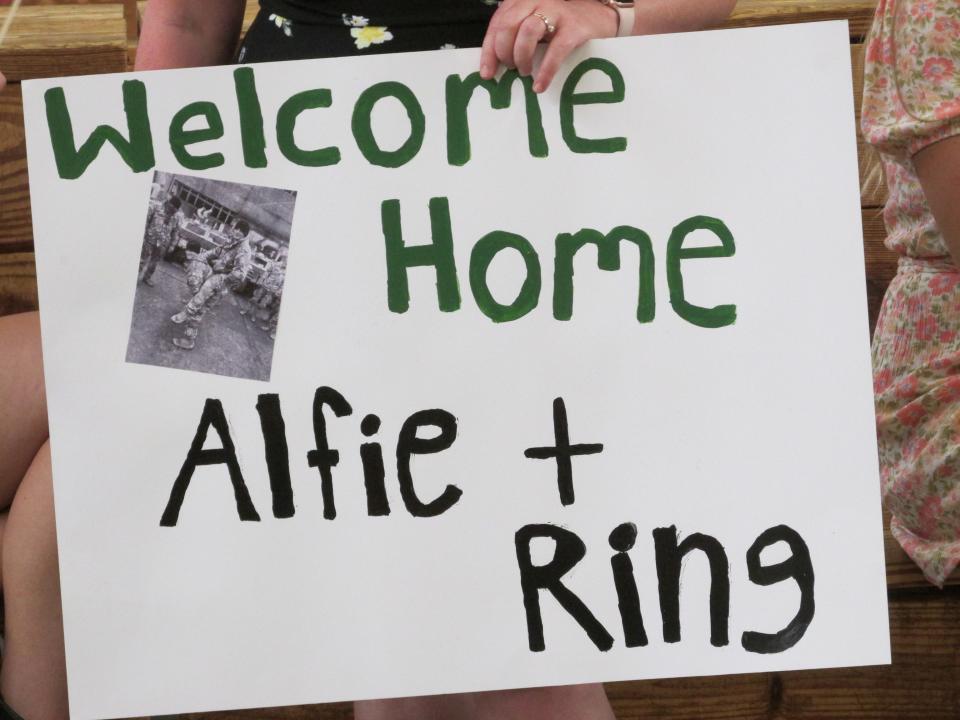 Megan Rylander holds a sign to welcome back home her husband Pfc. Alf Rylander and his commrader "Ring," Tuesday, June 28, 2022, after being deploye for more than four months to Poland.