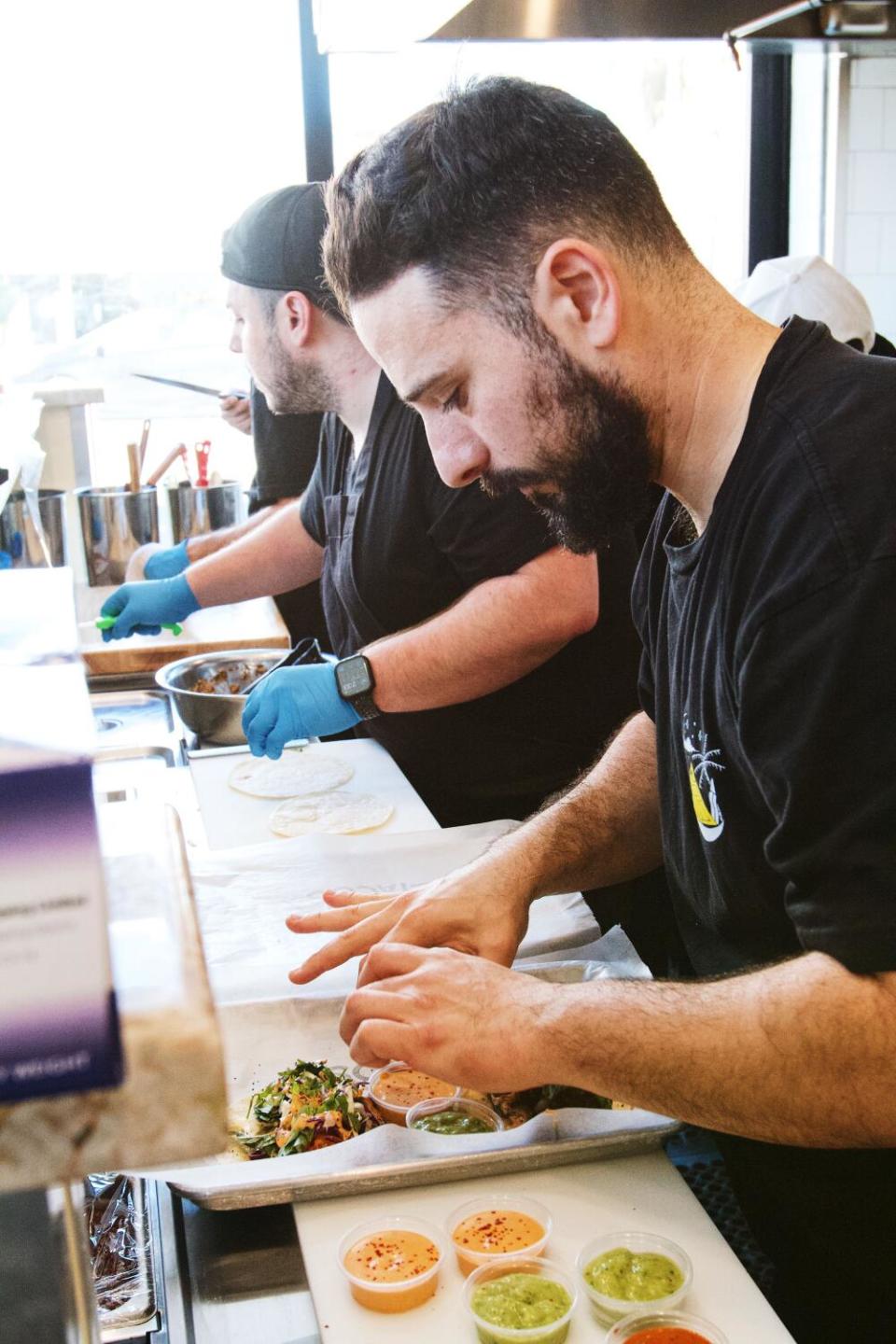 Armen Martirosyan assembles a taco tray with another chef next to him