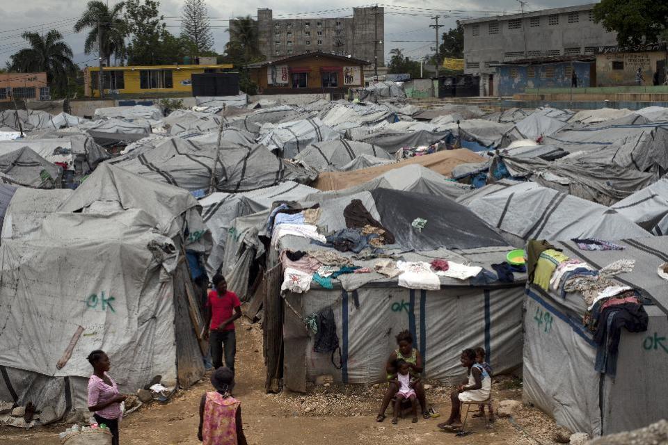 In this Thursday, April 26, 2012 photo, people live in a camp for those displaced by the 2010 earthquake, near the construction of the Oasis Hotel in Port-au-Prince, Haiti. This city is undergoing the largest hotel building boom in its history, raising expectations that investors will soon fill those air-conditioned rooms looking to build factories, tourist infrastructure and other amenities that will help Haiti bounce back from the 2010 earthquake that killed hundreds of thousands of people. (AP Photo/Ramon Espinosa)