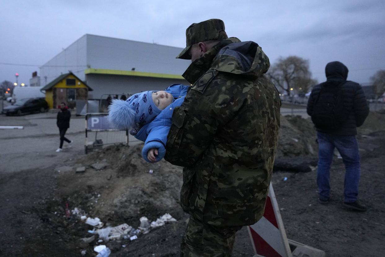 A Polish soldier carries a baby of a Ukrainian refugee upon their arrival at the border crossing in Medyka, southeastern Poland, Wednesday, March 2, 2022. Seven days into the war, roughly 874,000 people have fled Ukraine and the U.N. refugee agency warned the number could cross the 1 million mark soon.