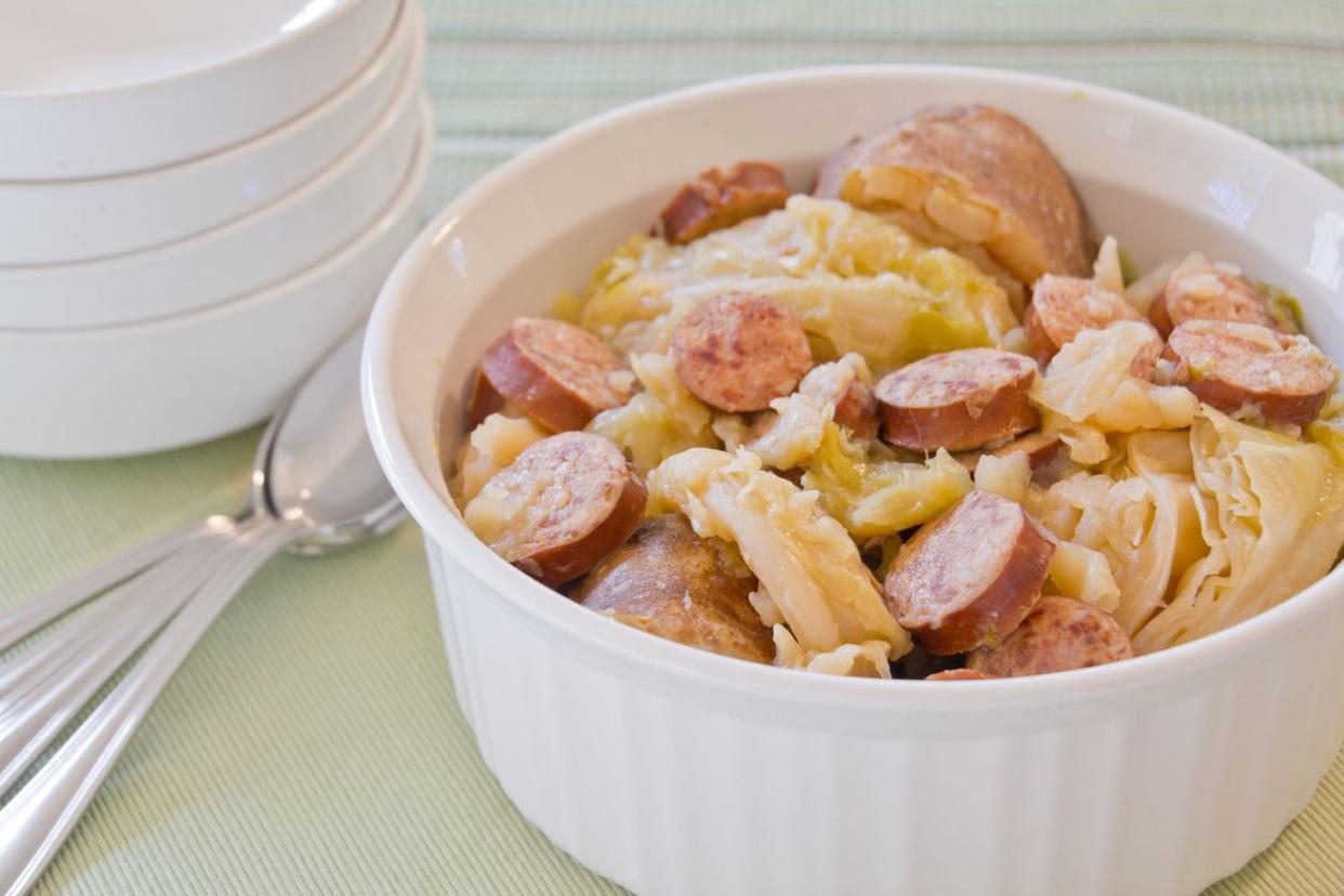 A one dish crock pot meal of cooked cabbage, smoked sausage, and potatoes