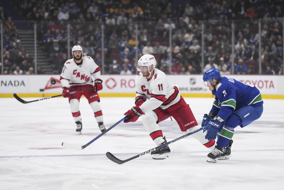 Carolina Hurricanes' Jordan Staal (11) and Vancouver Canucks' Jack Rathbone (3) vie for the puck during the first period of an NHL hockey game in Vancouver, British Columbia, on Monday, Oct. 24, 2022. (Darryl Dyck/The Canadian Press via AP)