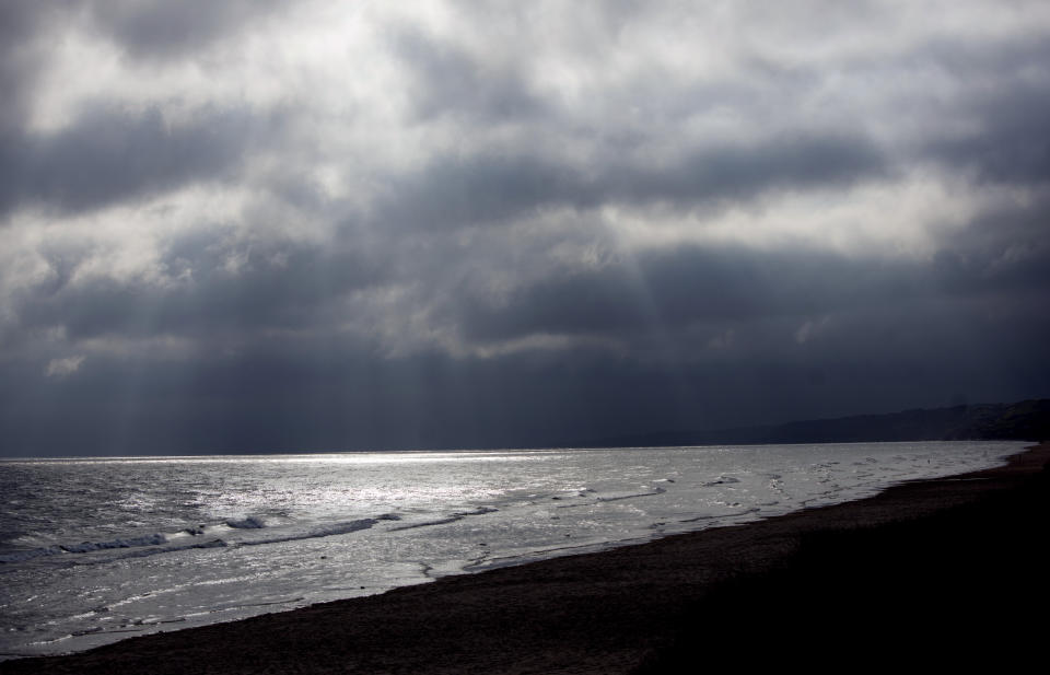 In this May 2, 2019, photo, the sun shines through storm clouds on Omaha Beach in St. Laurent-sur-Mer, Normandy, France. Allied troops first landed on Normandy's beaches on June 6, 1944, to begin the liberation of Europe from years of Nazi occupation. (AP Photo/Virginia Mayo)