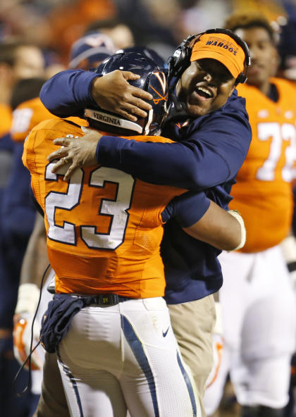 Virginia head coach Mike London, right, hugs Virginia running back Khalek Shepherd (23) after a touchdown during the second half of an NCAA college football game in Charlottesville, Va., Saturday, Nov. 22, 2014. Virginia won the game 30-13. (AP Photo/Steve Helber)