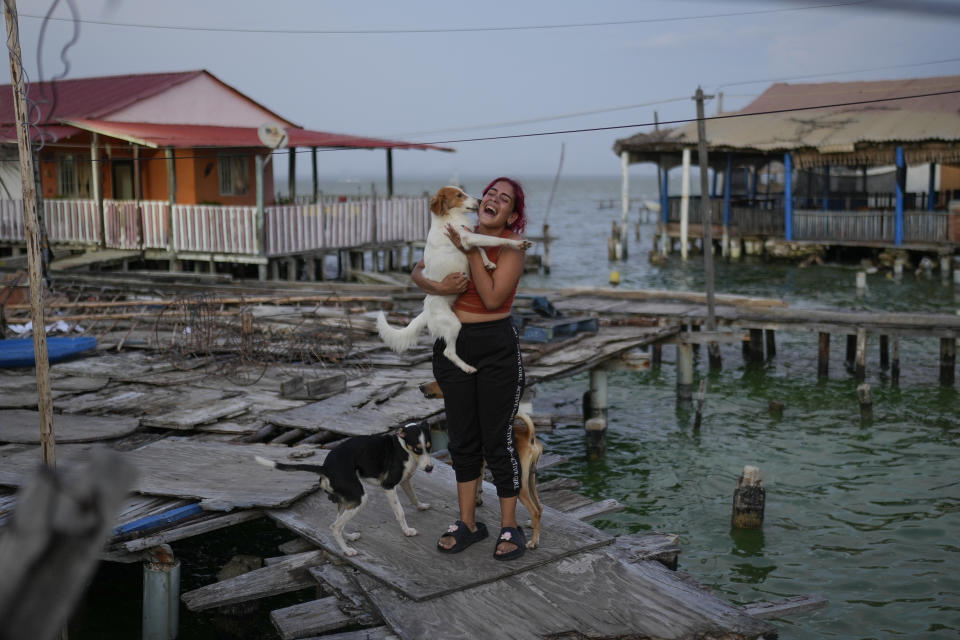 Una mujer juega con sus perros en el vecindario de Santa Rosa de Agua en Maracaibo, Venezuela, el lunes 22 de julio de 2024. Las elecciones presidenciales del país se han fijado para el 28 de julio. (AP Foto/Matias Delacroix)