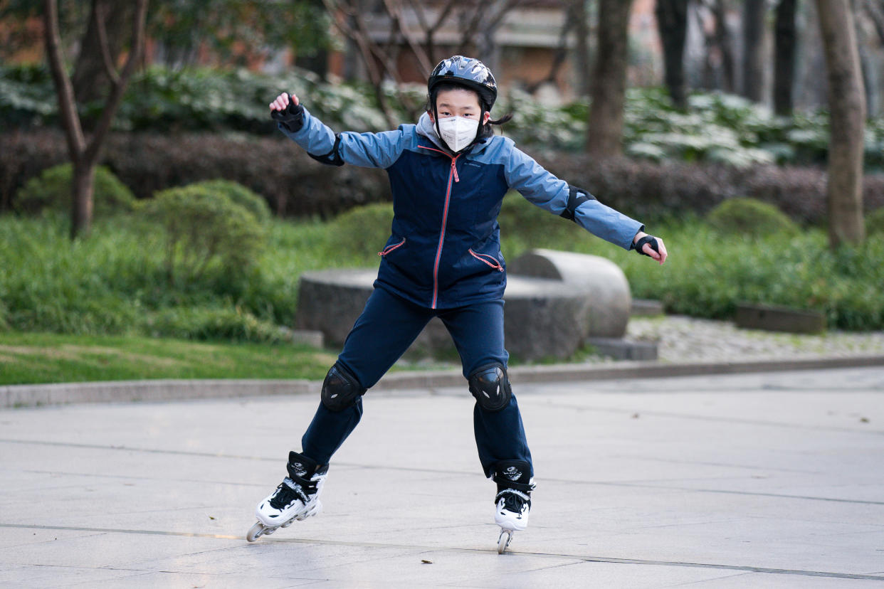 SHANGHAI, CHINA - MARCH 05: A young boy wearing a protective mask rides roller-skates in Xujiahui Park on March 05, 2020 in Shanghai, China. Twenty-one of mainland China's 31 regions have lowered emergency response levels on the flu-like epidemic by March 1, allowing greater movement of people and goods and a recovery in business activity. Since the outbreak began in December last year, more than 80,000 cases have been confirmed in China, with the death toll rising to more than 3,000. As of today, the number of cases of new coronavirus COVID-19 being treated in China dropped to approximately 25,400 in China, in what the World Health Organization (WHO) declared to raises coronavirus threat assessment to “very high” across the world by the end of February. (Photo by Yifan Ding/Getty Images)