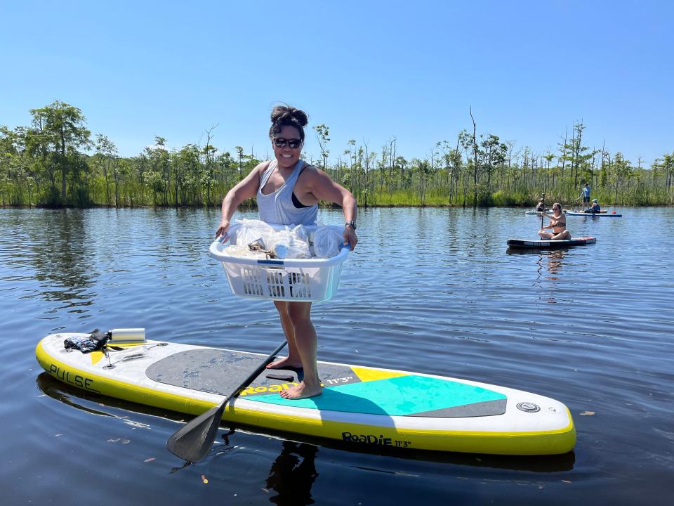 A paddleboarder holds a laundry basket filled with bags of trash while participating in a cleanup event on Goodby's Creek in Jacksonville. More than 29,000 pounds of garbage were collected during cleanup events along the St. Johns River this spring.
