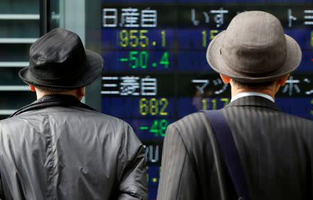 Men look at a stock quotation board showing share prices of Nissan Motor Co (top) and Mitsubishi Motors outside a brokerage in Tokyo, Japan November 20, 2018. REUTERS/Toru Hanai