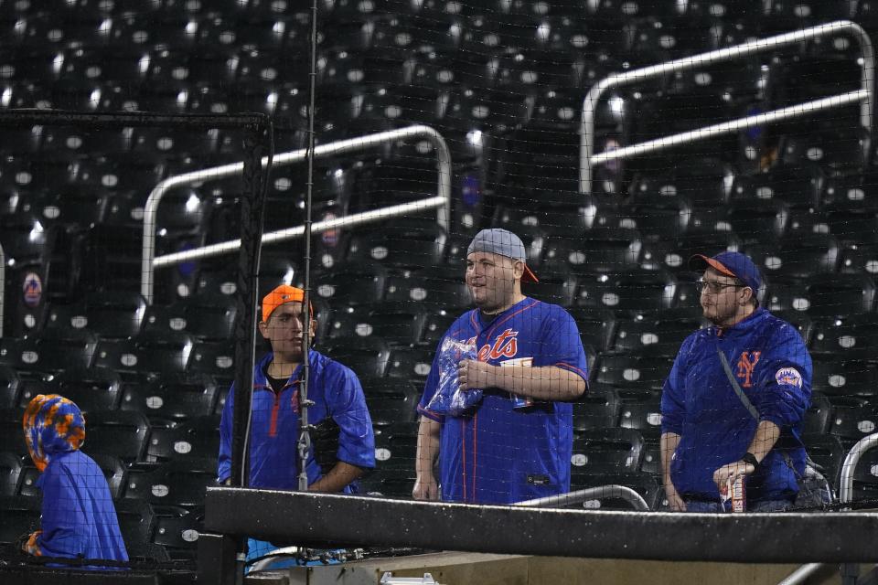 New York Mets fans watch grounds crew members work on the field during a rain delay in the team's baseball game against the Miami Marlins early Friday, Sept. 29, 2023, in New York. (AP Photo/Frank Franklin II)