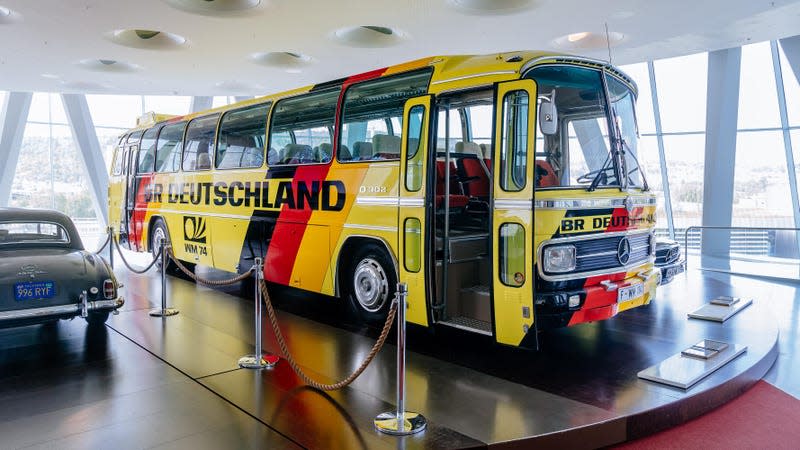 A pale yellow bus with German tricolor stripes on a platform