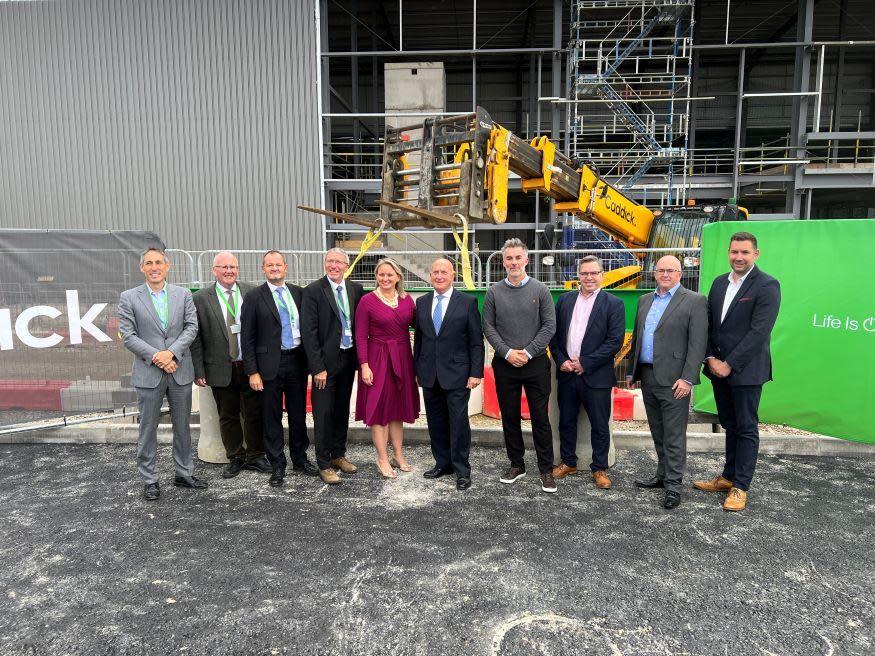 A group of people, including North Yorkshire mayor David Skaith stand in front of the construction of the new Schneider plant in Scarborough