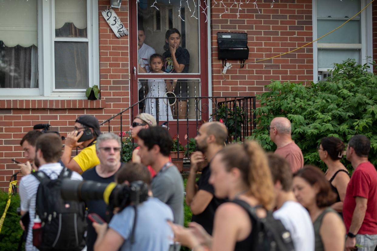 A family looks outside of their front door near the home of the mother of the man detained in the mass shooting at a Fourth of July parade on July 4, 2022 in Highland Park, Illinois. 