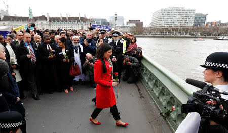 A woman places a red rose on Westminster Bridge during an event to mark one week since a man drove his car into pedestrians then stabbed a police officer in London, Britain, March 29, 2017. REUTERS/Stefan Wermuth