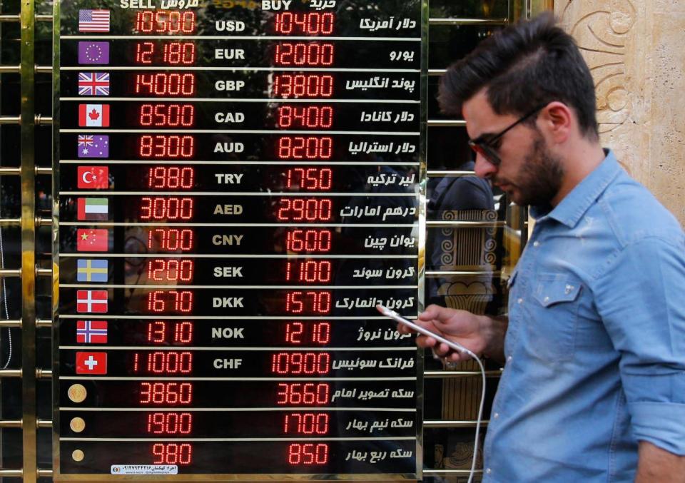 An Iranian checks the currency rates (EPA)