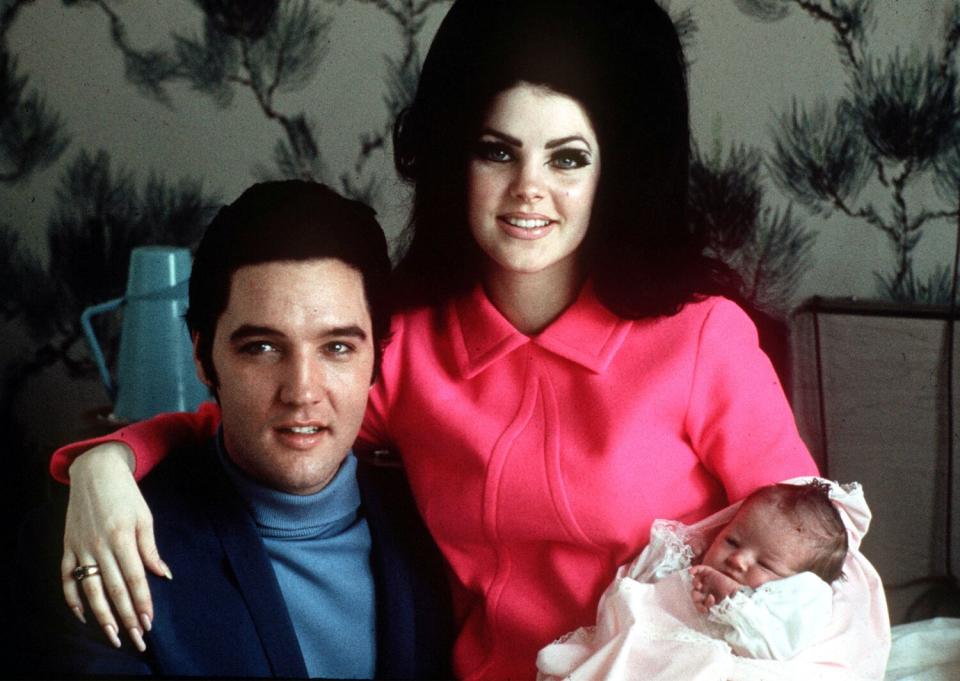 A man and woman pose for a photo with their newborn daughter