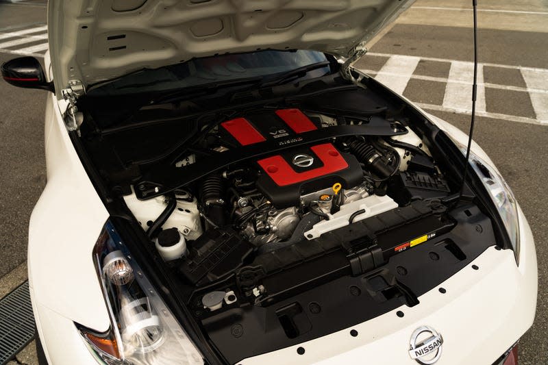 a nissan 370z fairlady nismo with the hood open, zoomed in on the engine