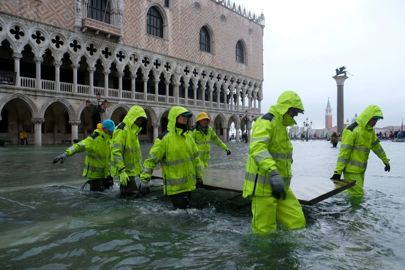 Workers are seen in the flooded St.Mark's Square during a period of seasonal high water in Venice