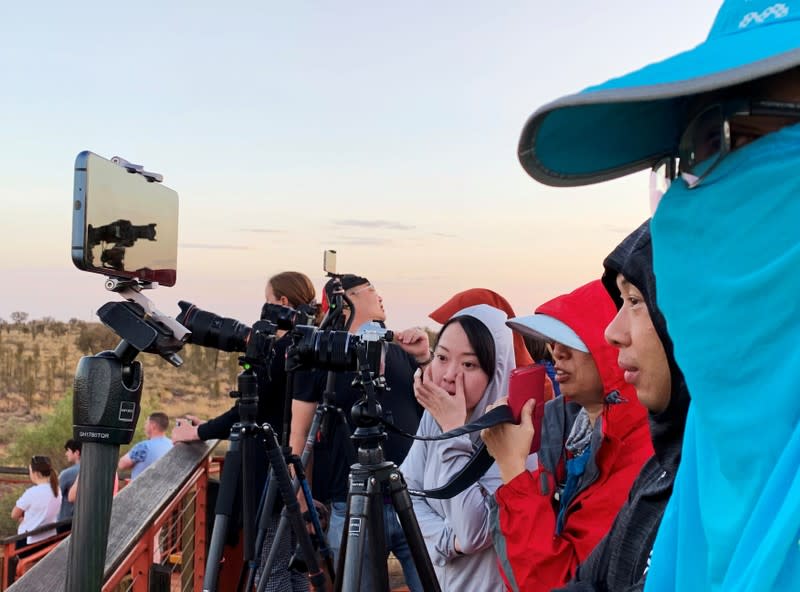 People view Uluru, the day before a permanent ban on climbing the monolith takes effect following a decades-long fight by indigenous people to close the trek, near Yulara