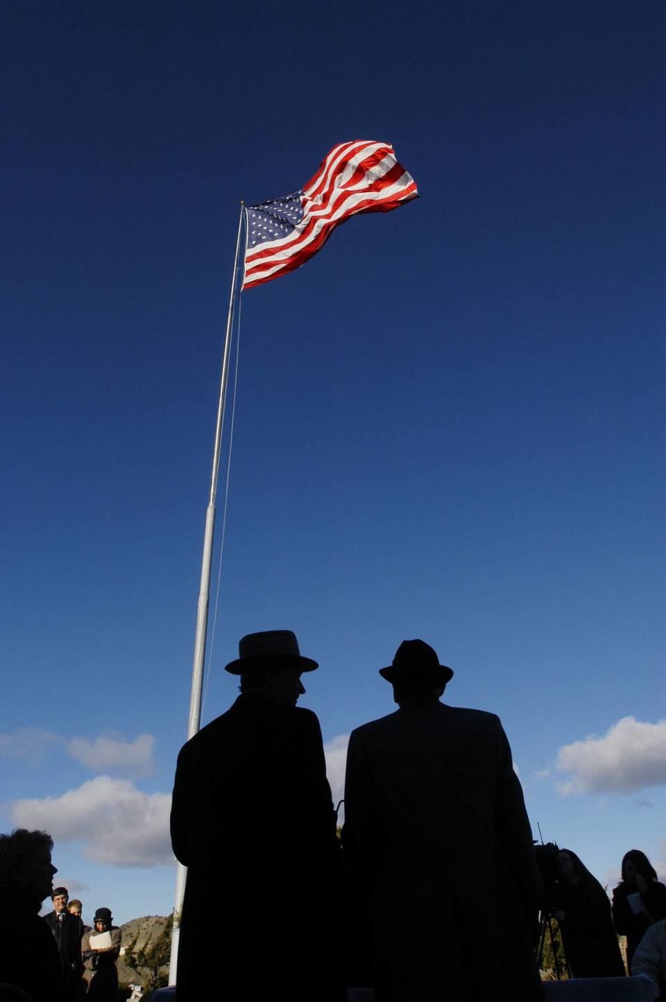 J.R. Simplot, right, and former Idaho Gov. Dirk Kempthorne stand under the familiar flag after the announcement of Simplot’s plans to donate his $2.8 million mansion to use as a governor’s residence.