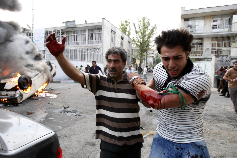 FILE - In this June 15, 2009 file photo, a protester allegedly injured by gunfire from a pro-government militia is helped by another protester near a rally supporting leading opposition presidential candidate Mir Hossein Mousavi in Tehran, Iran. The demonstrations that erupted after Iran admitted to accidentally shooting down a Ukrainian jetliner early Wednesday, Jan. 8, 2020, during a tense standoff with the United States, are the latest of several waves of protest going back to the 1979 Islamic Revolution — all of which have been violently suppressed. (AP photo/Vahid Salemi, File)