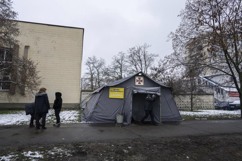 People stand in front of the heating tent "Point of Invincibly" in Kyiv, Ukraine, Monday, Nov. 28, 2022. (AP Photo/Evgeniy Maloletka)