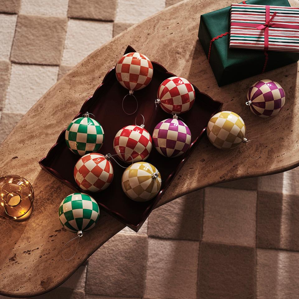 A stone coffee table on chequered rug with chequered Christmas baubles from the John Lewis Sugar & Spice range