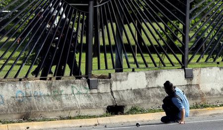 A member of the riot security forces points a gun through the fence of an air force base at David Jose Vallenilla, who was fatally injured during clashes at a rally against Venezuelan President Nicolas Maduro's government in Caracas, Venezuela June 22, 2017. REUTERS/Carlos Garcia Rawlins